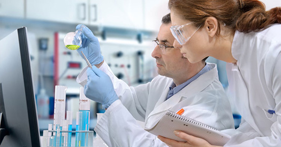 Técnicos de laboratorio con batas y guantes manipulando tubos de ensayo — formación para el empleo