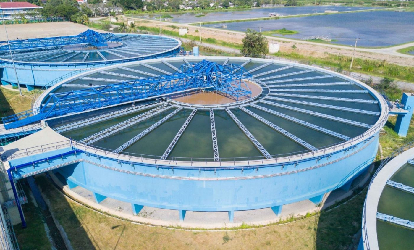 Tanque clarificador circular con puente metálico azul en planta de tratamiento de agua — mantenimiento industrial