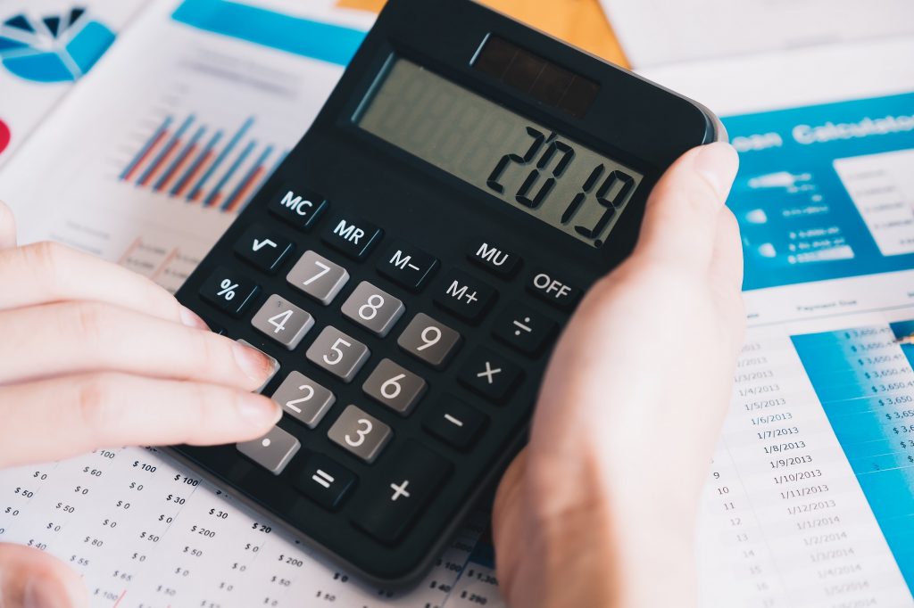 Calculadora con pantalla '2019' sobre hojas de contabilidad, cursos online