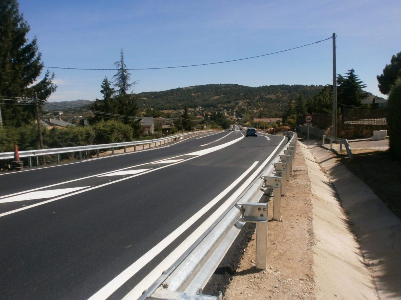 Carretera recién asfaltada con quitamiedos metálico y señal de 40, cursos sector industrial