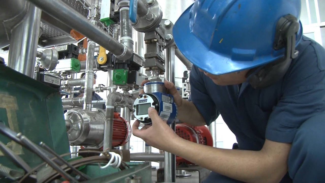 Operario con casco y protección auditiva realizando mantenimiento industrial en tuberías y válvulas