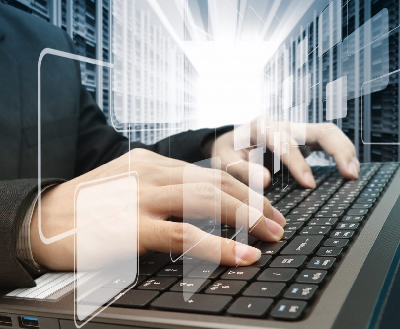 Manos tecleando en portátil frente a servidores, cursos online