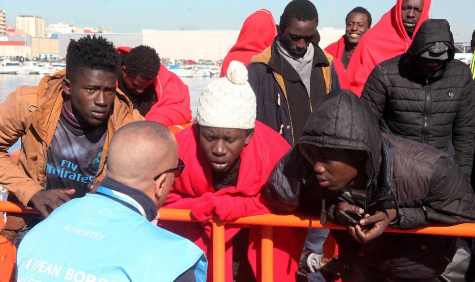 Personas migrantes hablando con un agente de Frontex en un muelle — formación para el empleo