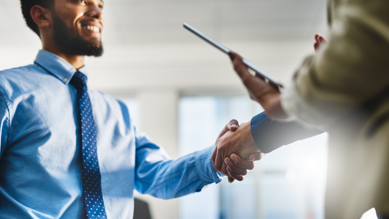 Hombre sonriente estrechando la mano en una oficina, formación para el empleo