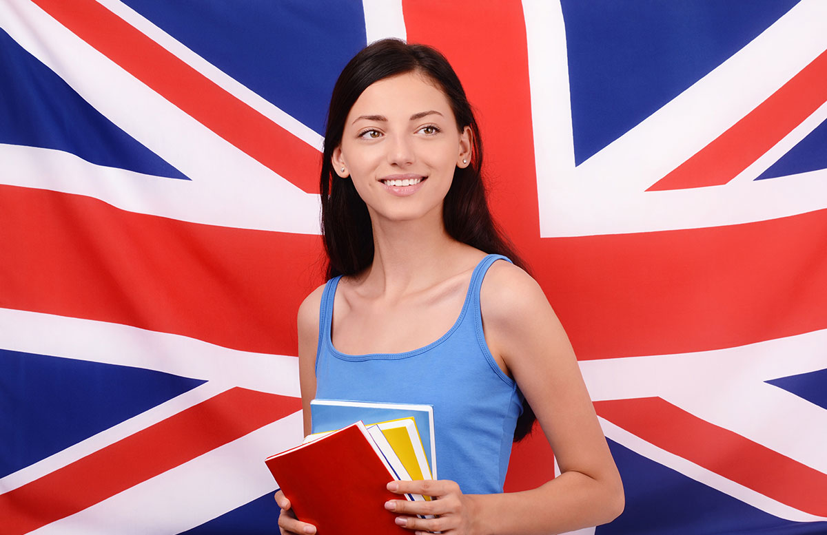 Joven con cuadernos delante de la bandera del Reino Unido, cursos online