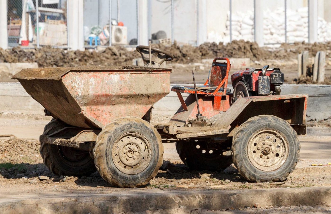 Dumper de obra pequeño con tolva frontal y ruedas cubiertas de barro