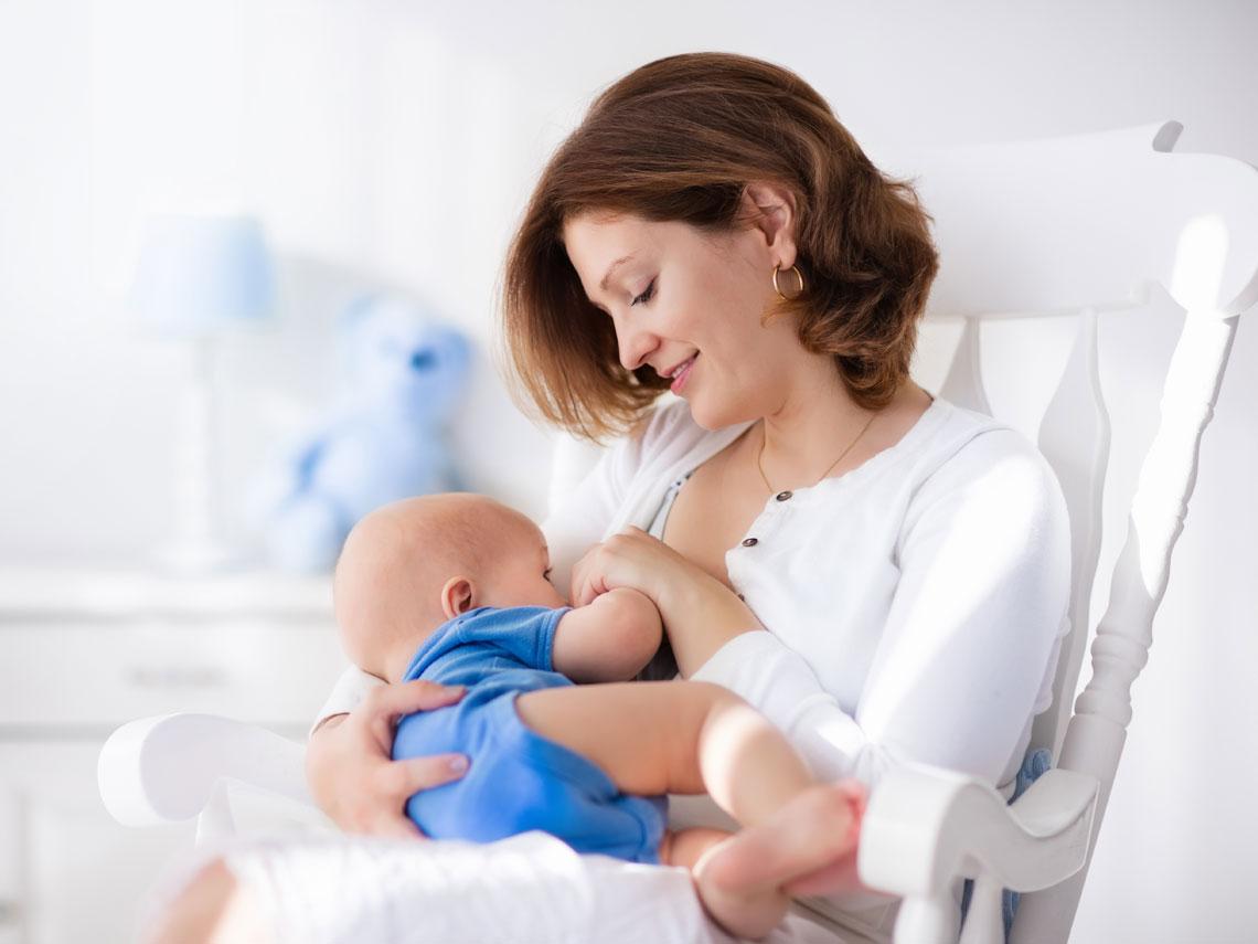 Madre amamantando a su bebé en una mecedora — formación para el empleo