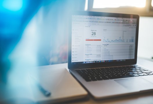 Portátil con panel de analíticas y libreta al lado, cursos online