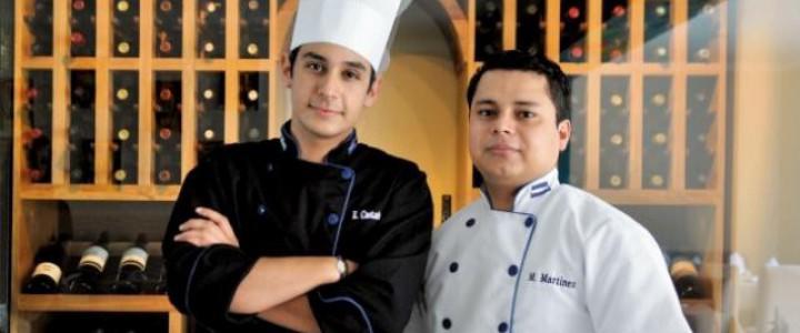 Dos cocineros con uniforme y gorro frente a estanterías de vino, certificado de profesionalidad