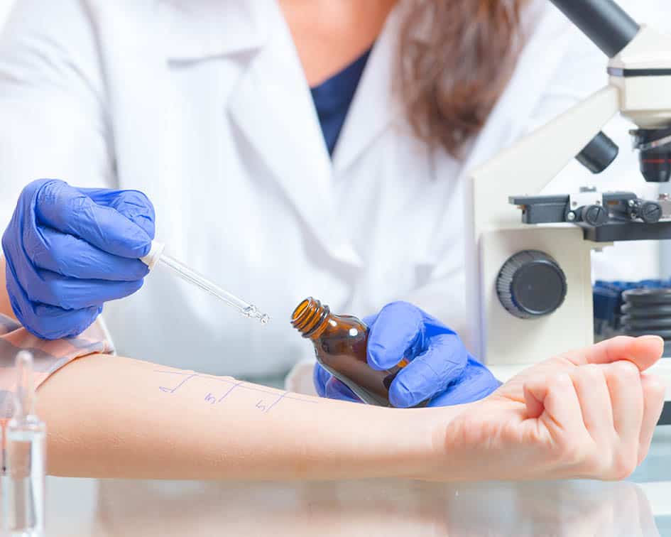 Prueba cutánea en antebrazo con pipeta y guantes azules, cursos online