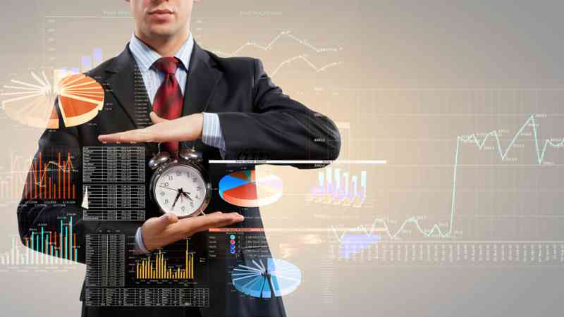 Hombre de traje sosteniendo un reloj despertador con gráficos digitales superpuestos - cursos online