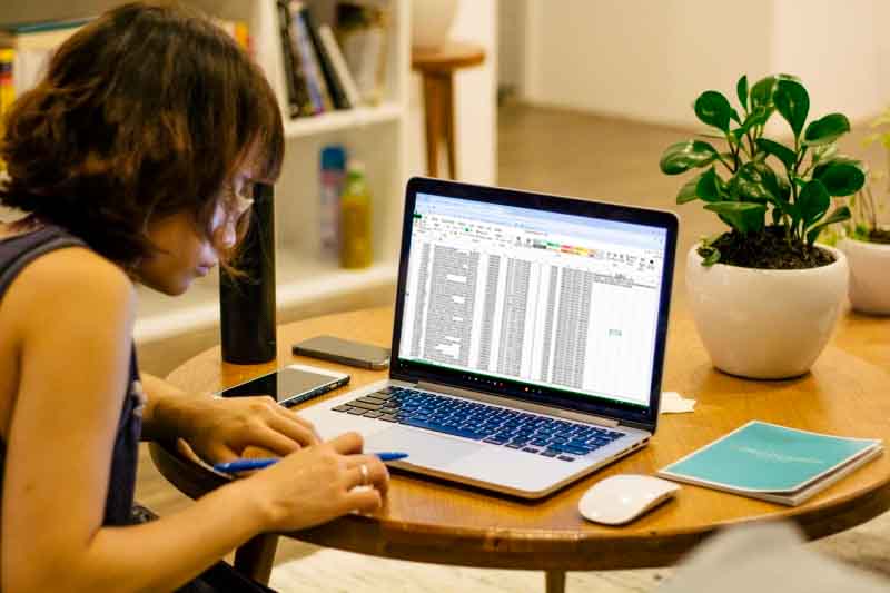 Persona trabajando en portátil con hoja de cálculo en mesa de madera, cursos online