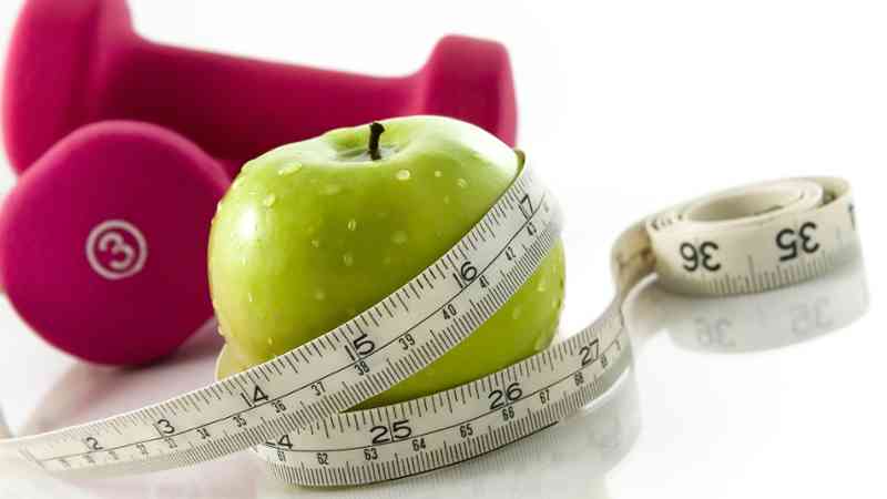 Manzana verde con cinta métrica y pesa rosa, cursos online
