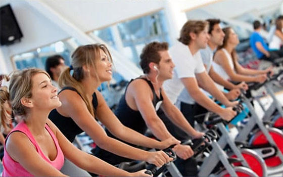Clase de spinning en estudio con varias personas en bicicletas estáticas, cursos online