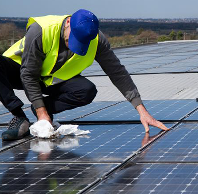Operario limpiando paneles solares en cubierta — formación para el empleo