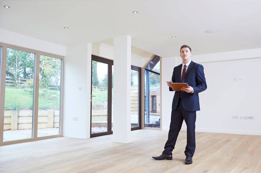 Hombre con traje y carpeta en sala vacía y luminosa con suelo de madera, formación para el empleo