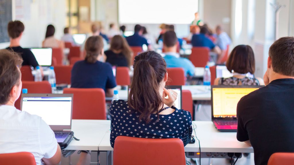 Personas sentadas en aula con portátiles, formación para el empleo
