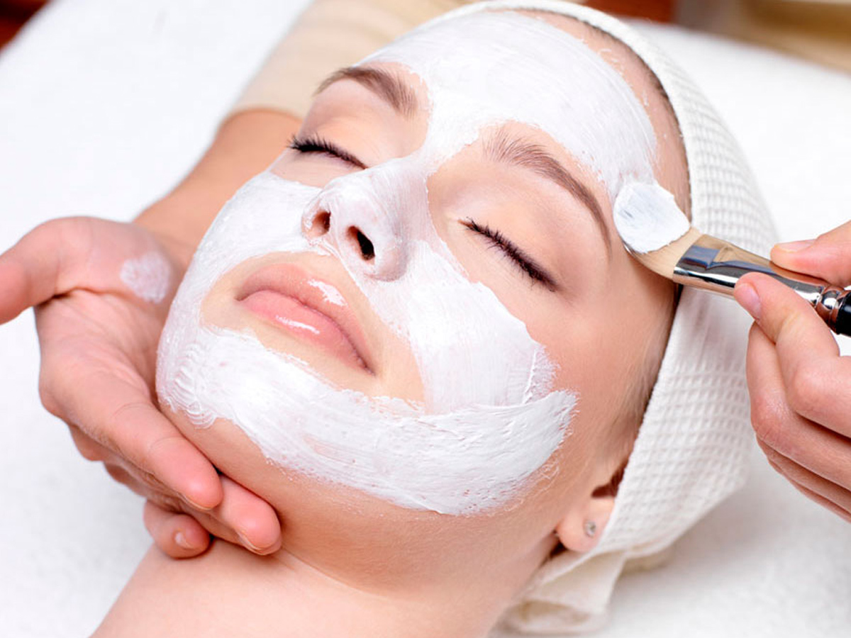 Mujer con mascarilla facial blanca aplicada por una esteticista (cursos online)