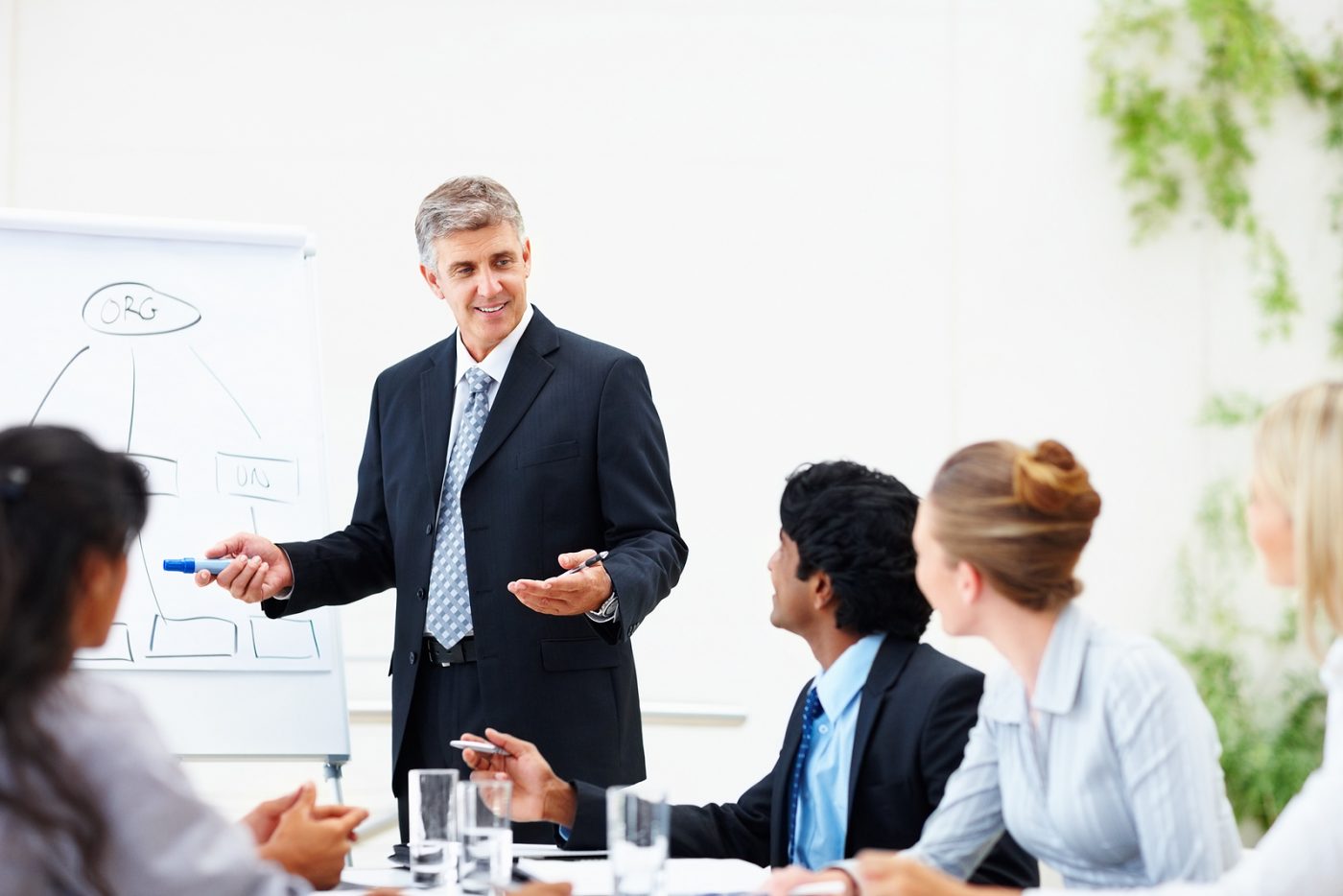 Formador señalando un rotafolio ante un grupo de asistentes — formación para el empleo