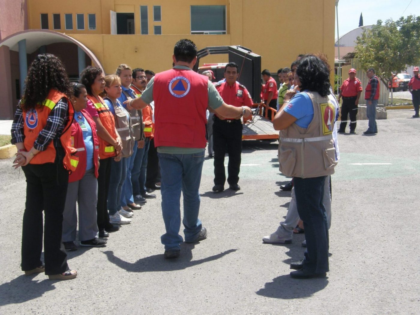 Instructor con chaleco rojo dirigiendo a voluntarios de protección civil en formación para asociaciones