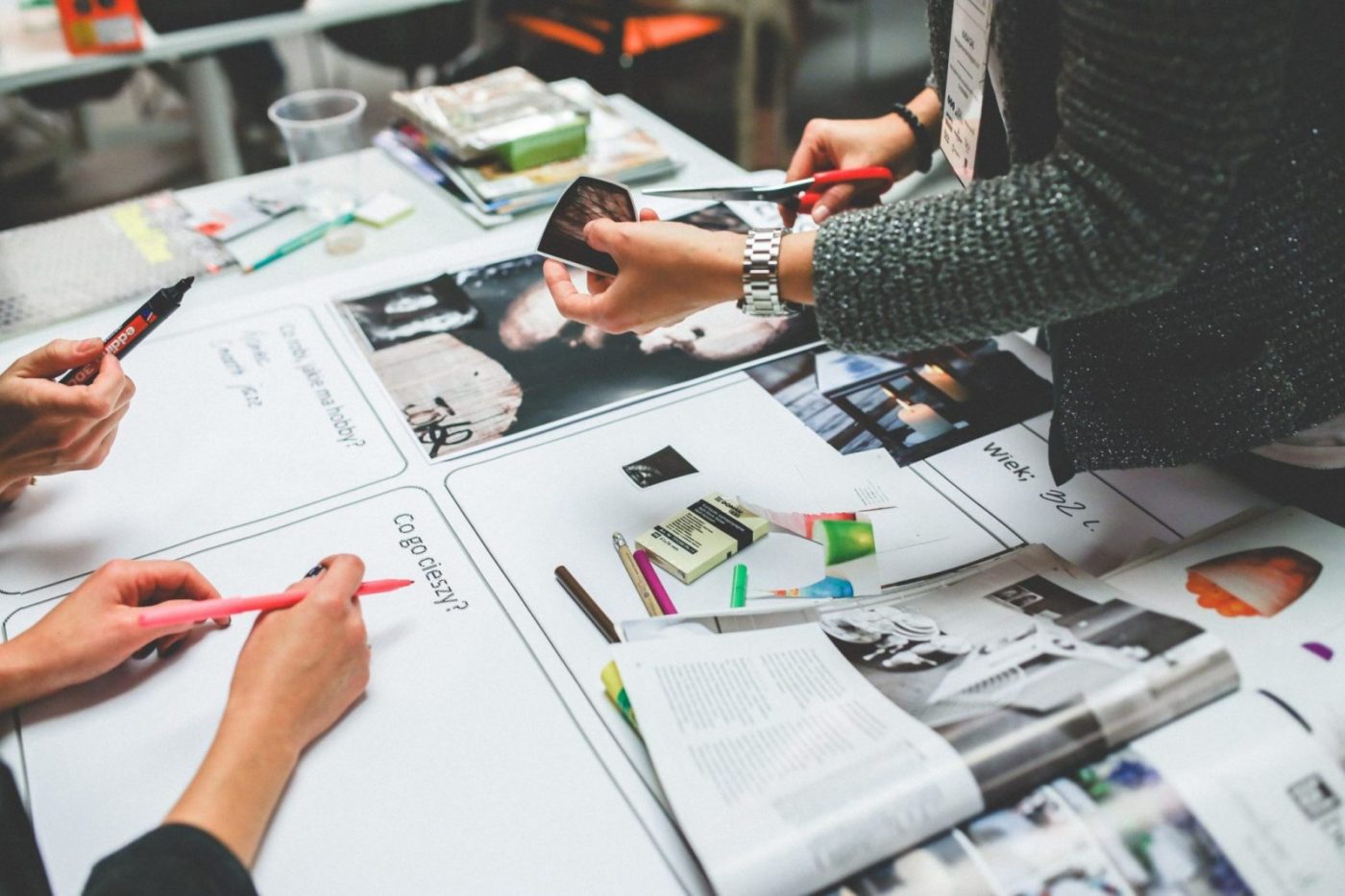 Mesa de taller con revistas, fotos recortadas y rotuladores — formación para el empleo