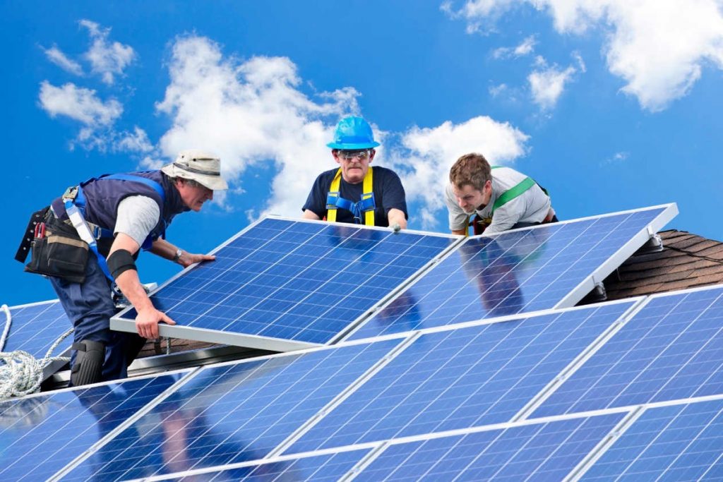 Tres operarios instalando paneles solares en tejado, cursos sector industrial