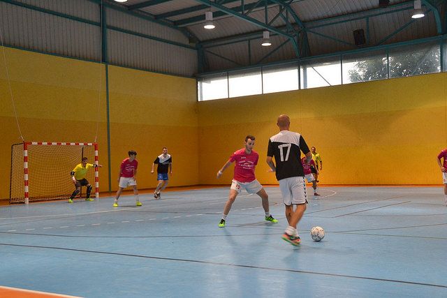 Jugador controlando balón en partido de fútbol sala en pista cubierta — formación para asociaciones