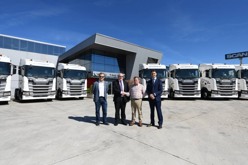 Cuatro hombres delante de una hilera de camiones Scania blancos (tractor)