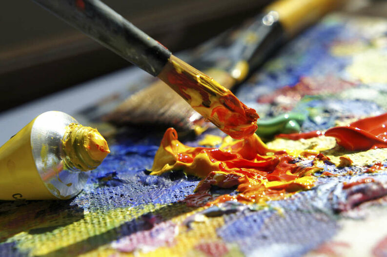 Pincel con pintura amarilla y roja sobre paleta y lienzo, cursos online