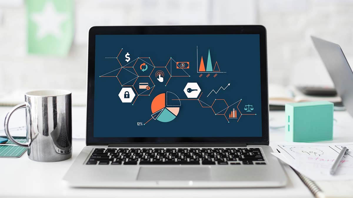 Portátil en escritorio con infografía y gráfico circular en la pantalla (cursos online)