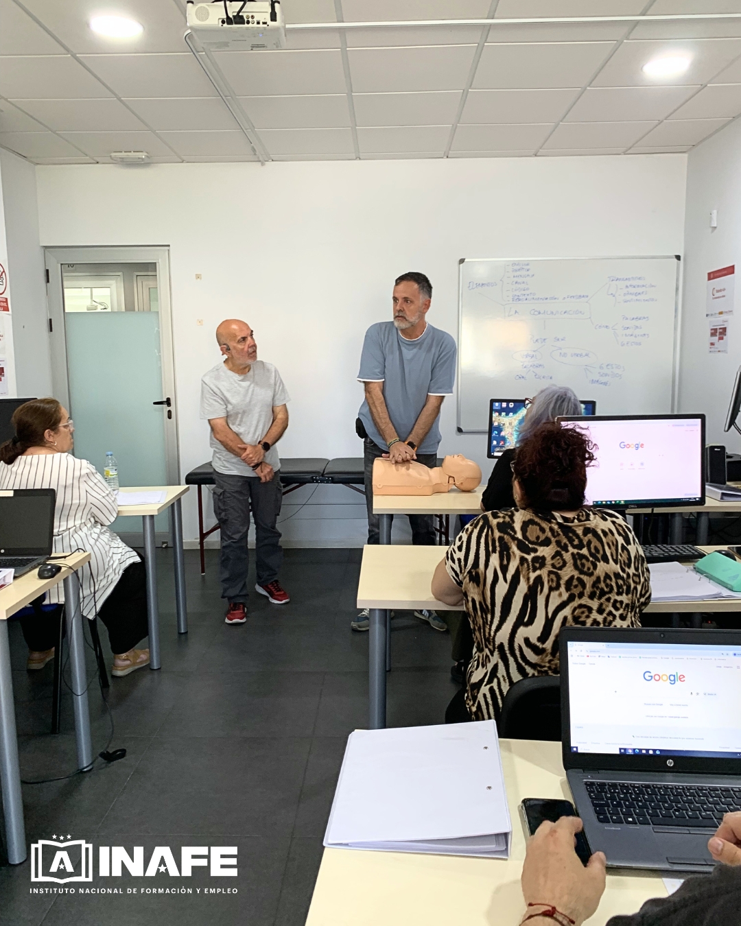 Instructor practicando RCP con maniquí frente a alumnos en aula de formación para el empleo