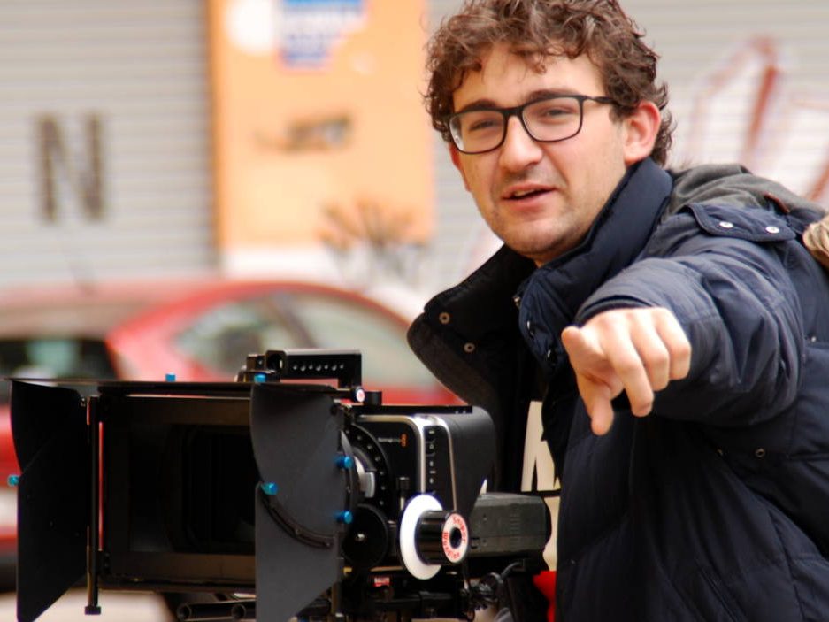 Hombre junto a cámara de cine profesional señalando, formación para el empleo