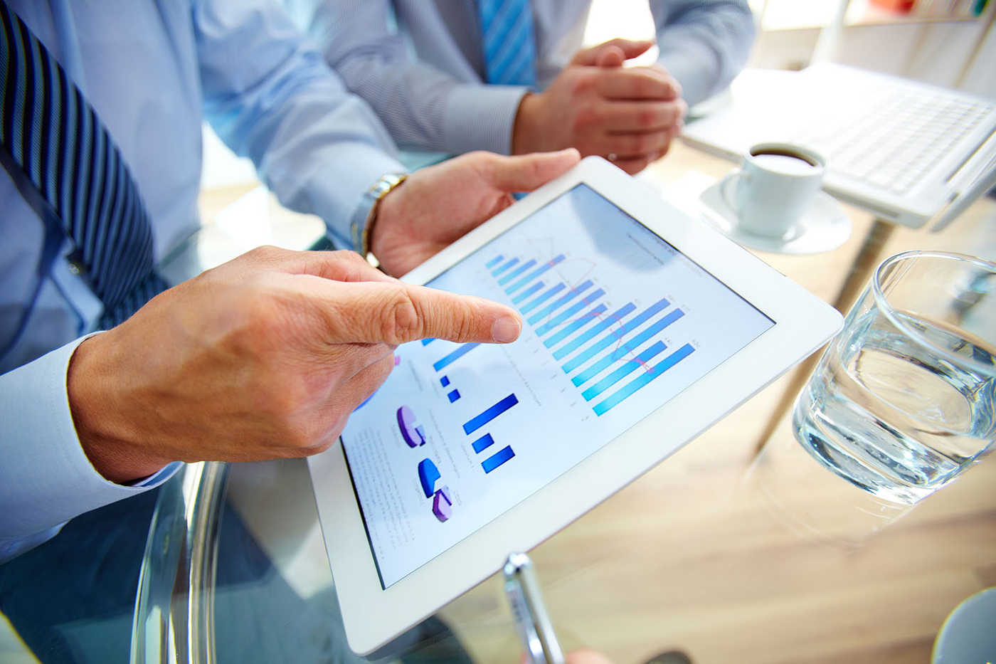 Mano señalando gráficos en tablet durante reunión, cursos online
