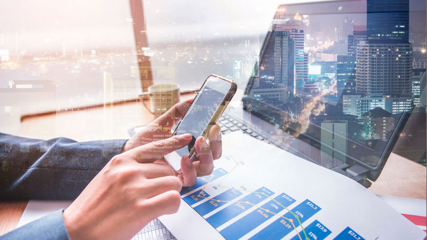 Manos usando un smartphone junto a un portátil y un informe con gráfico de barras — cursos online