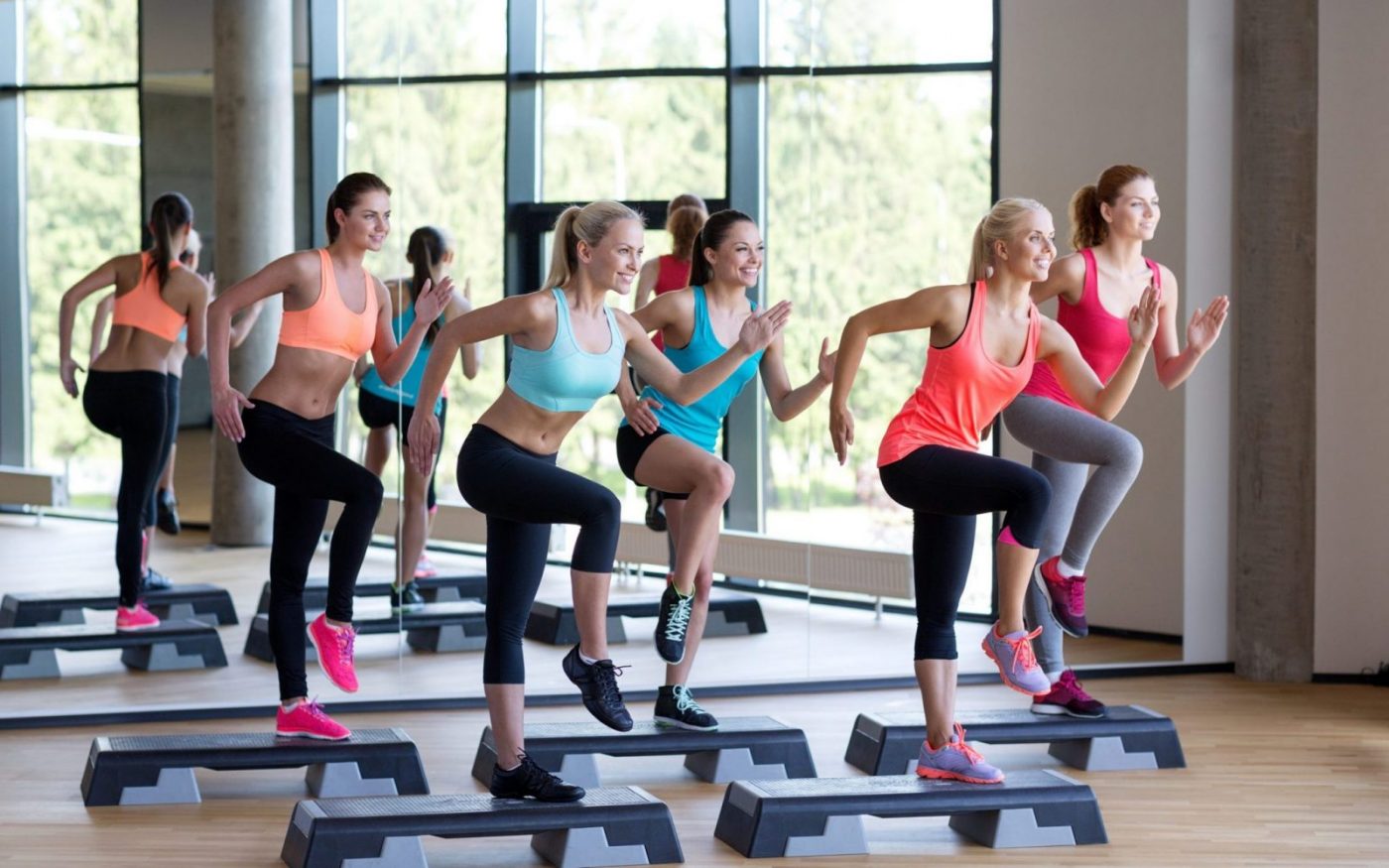 Clase de step aerobics en gimnasio con mujeres en plataformas, cursos online