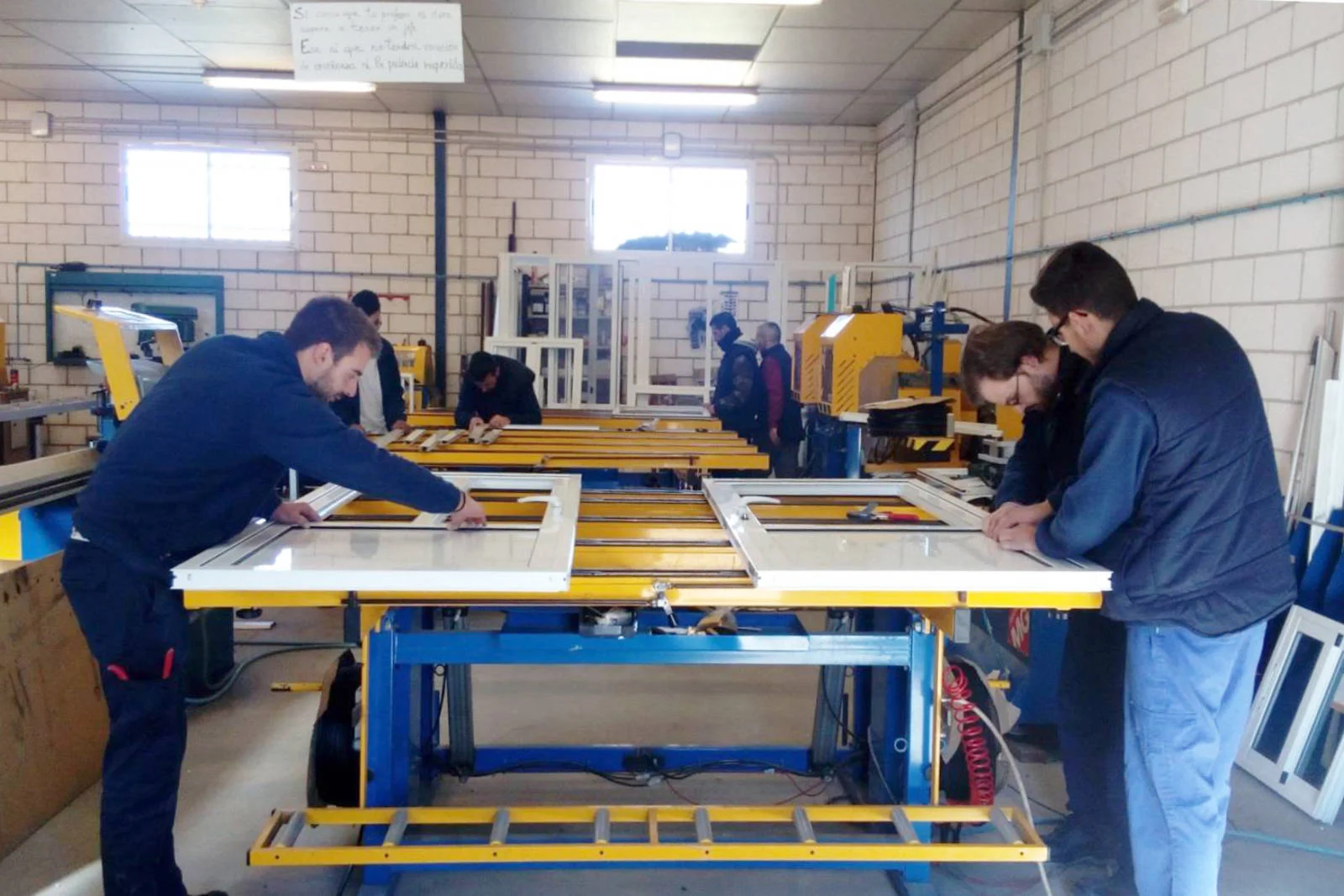 Alumnos ensamblando marcos en mesa de taller (cursos con prácticas en empresa)