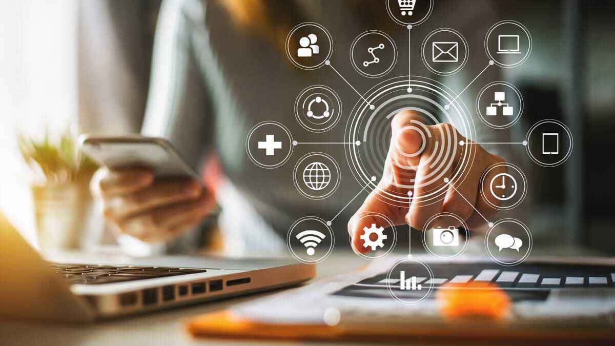 Mano señalando iconos digitales sobre portátil y smartphone, cursos online