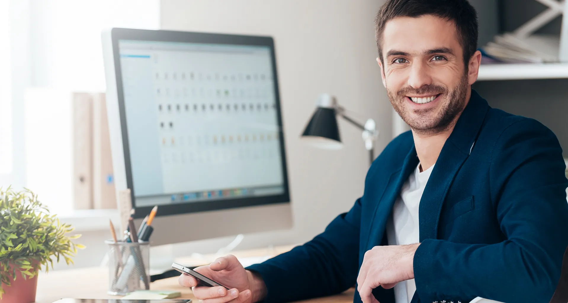 Hombre en oficina con ordenador y móvil, cursos online