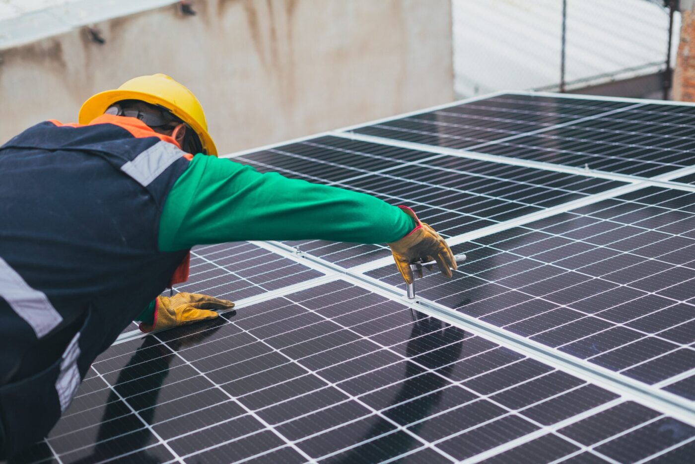 Técnico con casco ajustando un panel fotovoltaico en tejado, mantenimiento industrial