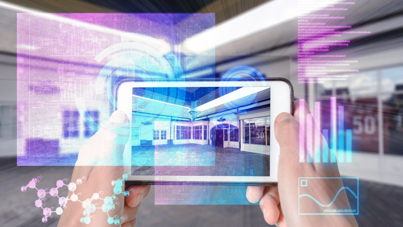 Teléfono móvil con superposiciones digitales mostrando un local vacío, manos sosteniéndolo — cursos online