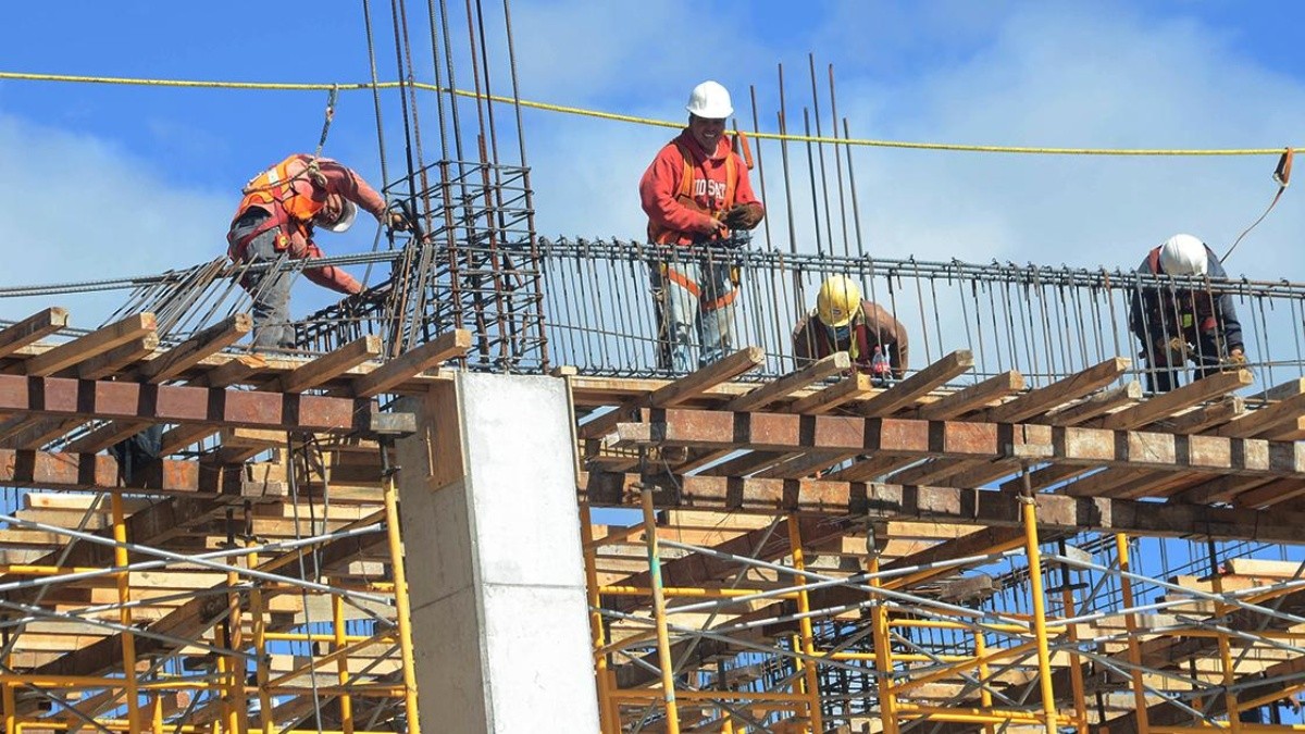 Trabajadores en obra sobre andamio con armaduras de acero, cursos sector industrial