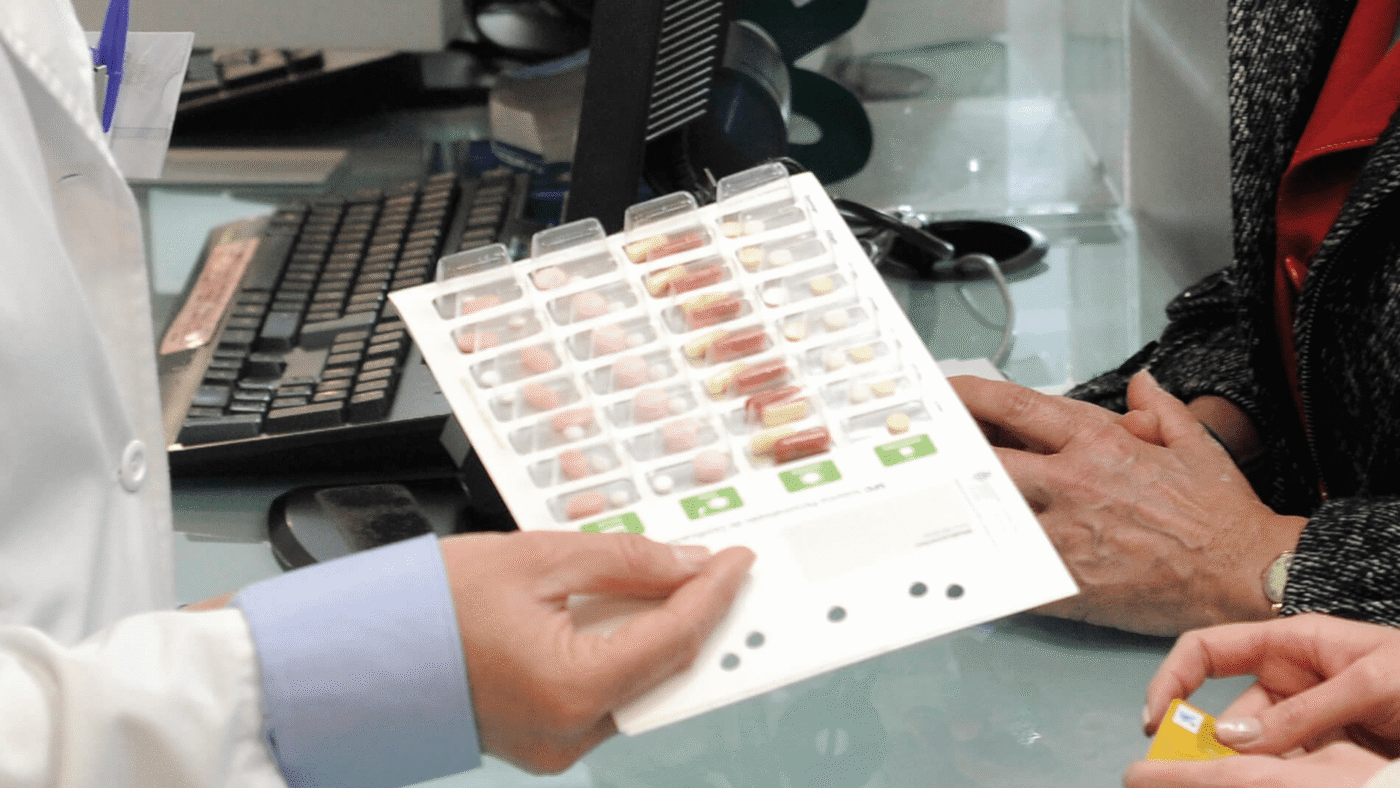 Hoja SPD con blisters de medicación en manos de un profesional de farmacia — formación para el empleo