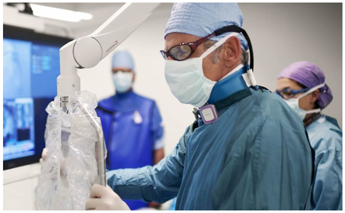 Cirujano con mascarilla y bata manipulando equipo médico articulado en quirófano, cursos online