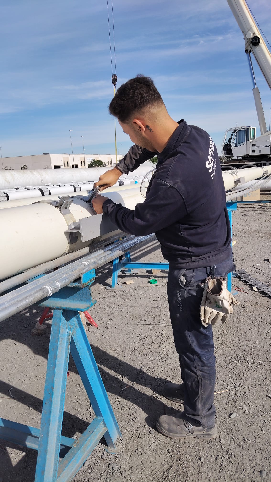 Trabajador tubero ajustando una abrazadera en una tubería blanca