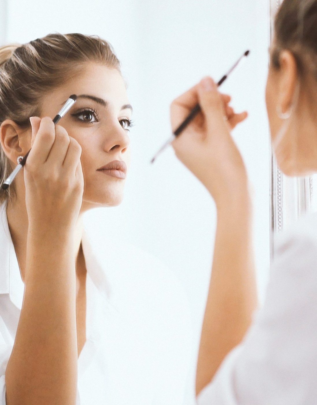 Mujer aplicándose sombra de ojos frente al espejo — cursos online