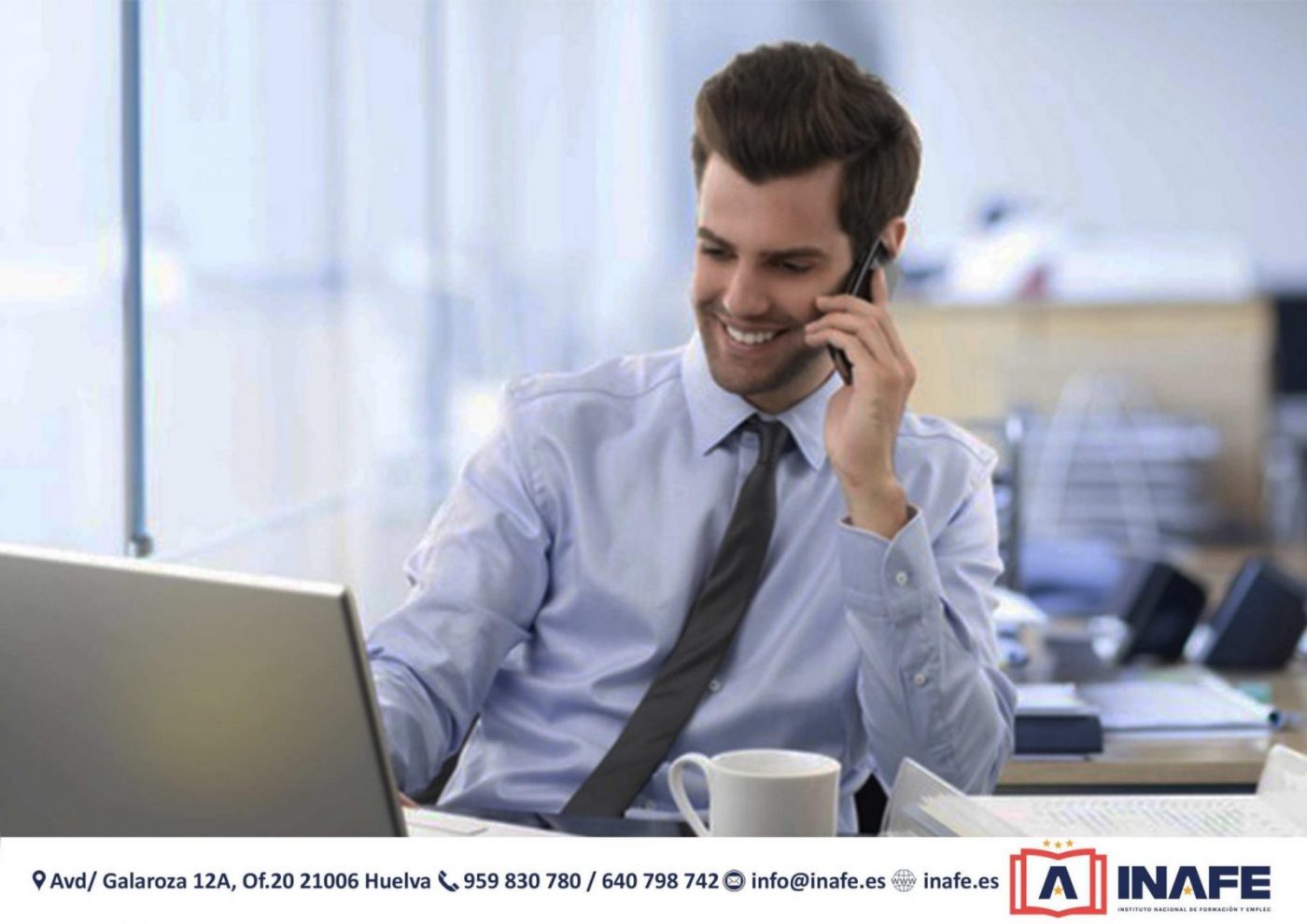 Hombre sonriente en oficina hablando por teléfono junto a un portátil; formación profesional Huelva
