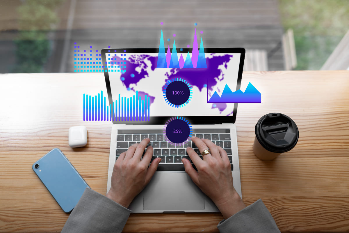 Manos tecleando en un portátil con mapa mundial y gráficos digitales en pantalla, cursos online