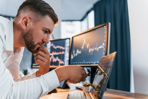 Hombre observando pantallas con gráficos financieros, cursos online