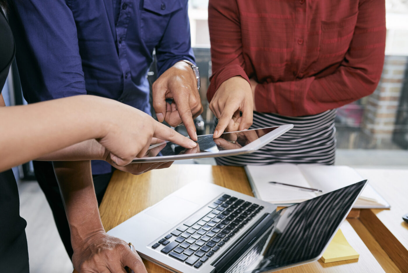 Manos señalando una tablet sobre un portátil, cursos online