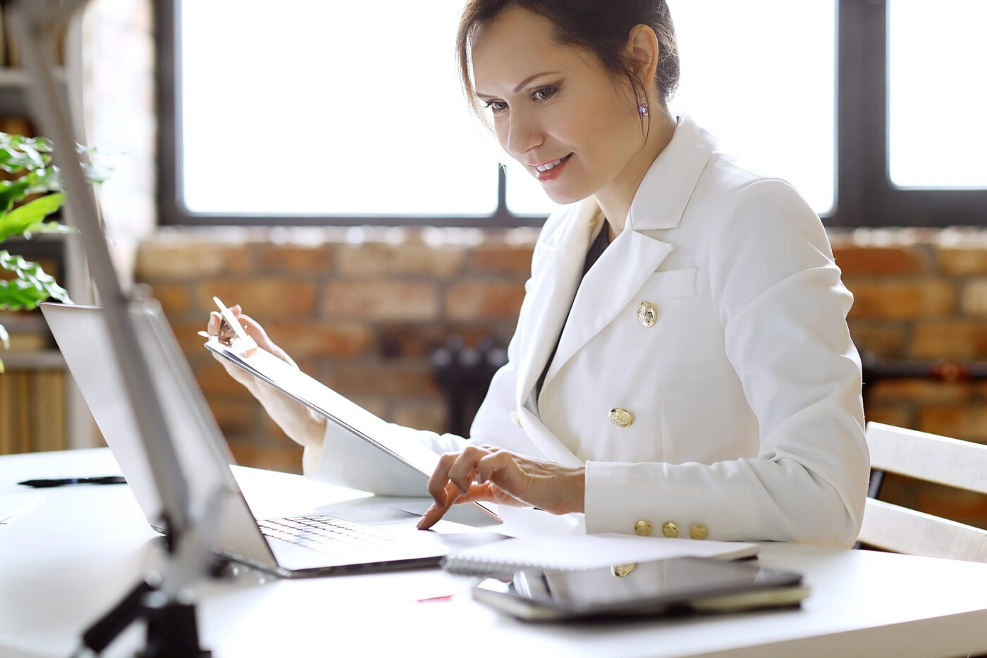 Mujer trabajando en portátil con documentos, cursos online